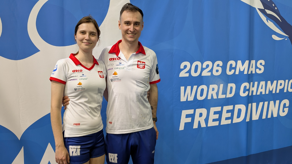 Bartosz Jakubowiak with a Polish teammate in front of the 2026 CMAS World Championship Freediving banner